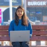 Teenager Sitting on Bench with Laptop