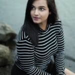 Woman in Striped Shirt Sitting on Rocks on River Bank