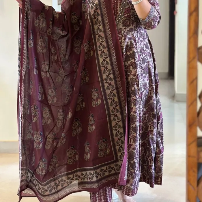 A timeless maroon cotton suit set featuring delicate beige floral motifs, enhanced with detailed printed yoke and sleeves. The set includes a flowy A-line kurta, matching straight pants, and a beautifully bordered printed dupatta. A must-have for your casual ethnic wardrobe or breezy daywear.
