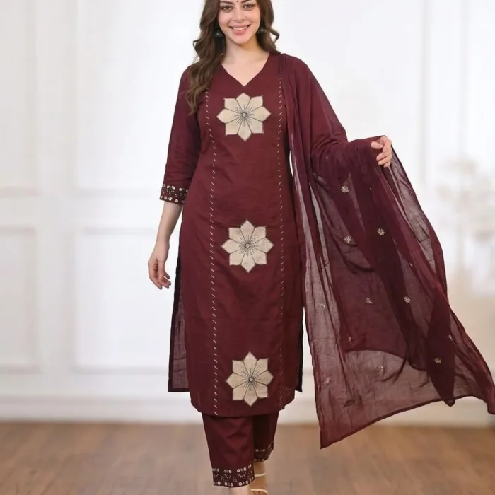 A woman wearing a deep wine maroon heavy cotton kurti pant set with large beige floral embroidery patches and a matching dupatta.