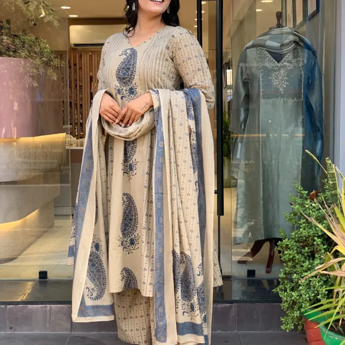 A woman stands outside a boutique wearing a featuring a beige Morgan Silk Digital Paisley Print Kurti Pant Set with matching dupatta